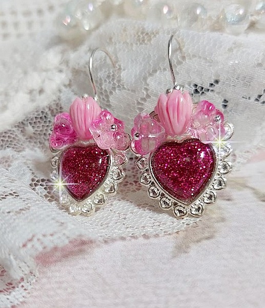 BO C&oelig;ur Ardent mont&eacute;es avec des dormeuses argent&eacute;es &agrave; laquelle s&rsquo;ajoute des c&oelig;urs paillet&eacute;s en r&eacute;sine Fuchsia. Ils sont orn&eacute;s d&rsquo;un bouquet de fleurs en verre &agrave; la couleur Rose pour un style romantique