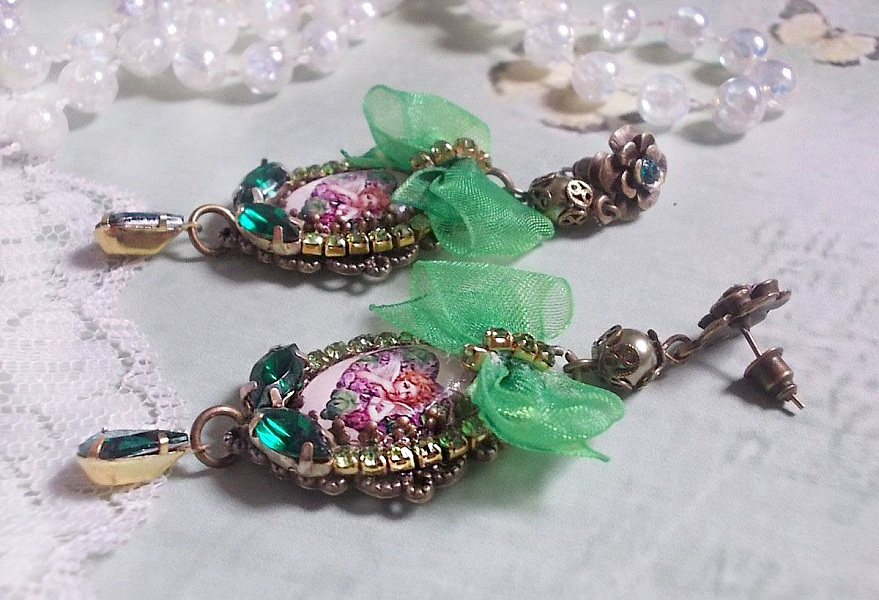 BO C&oelig;ur d&rsquo;Anges avec des cabochons d&rsquo;un petit ange orn&eacute;s d&rsquo;une cha&icirc;ne strass, navettes, poires et cabochons en Cristal. S&rsquo;ajoute des rubans organza sur pendentifs et clous en forme de fleurs.
