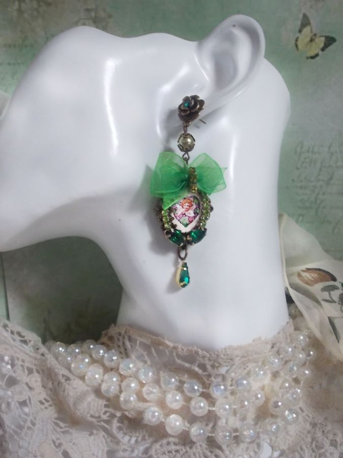 BO C&oelig;ur d&rsquo;Anges avec des cabochons d&rsquo;un petit ange orn&eacute;s d&rsquo;une cha&icirc;ne strass, navettes, poires et cabochons en Cristal. S&rsquo;ajoute des rubans organza sur pendentifs et clous en forme de fleurs.