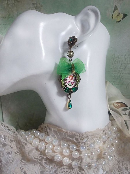 BO C&oelig;ur d&rsquo;Anges avec des cabochons d&rsquo;un petit ange orn&eacute;s d&rsquo;une cha&icirc;ne strass, navettes, poires et cabochons en Cristal. S&rsquo;ajoute des rubans organza sur pendentifs et clous en forme de fleurs.