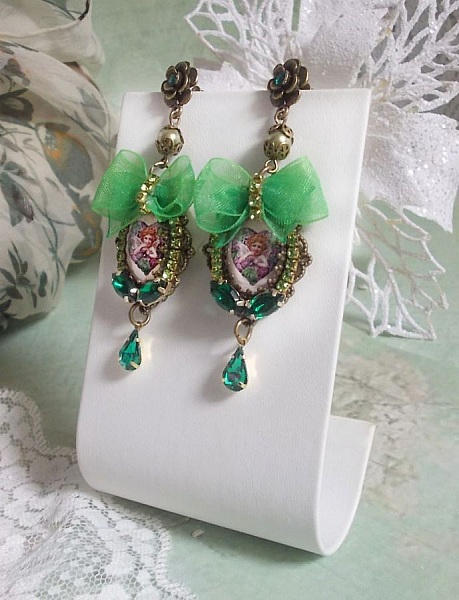 BO C&oelig;ur d&rsquo;Anges avec des cabochons d&rsquo;un petit ange orn&eacute;s d&rsquo;une cha&icirc;ne strass, navettes, poires et cabochons en Cristal. S&rsquo;ajoute des rubans organza sur pendentifs et clous en forme de fleurs.