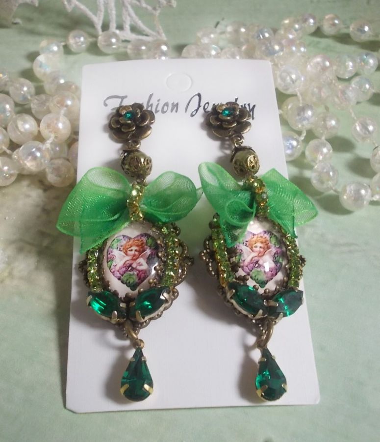 BO C&oelig;ur d&rsquo;Anges avec des cabochons d&rsquo;un petit ange orn&eacute;s d&rsquo;une cha&icirc;ne strass, navettes, poires et cabochons en Cristal. S&rsquo;ajoute des rubans organza sur pendentifs et clous en forme de fleurs.