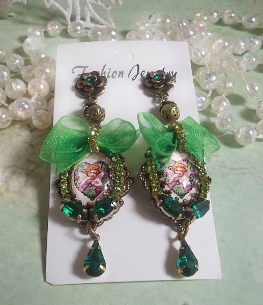 BO C&oelig;ur d&rsquo;Anges avec des cabochons d&rsquo;un petit ange orn&eacute;s d&rsquo;une cha&icirc;ne strass, navettes, poires et cabochons en Cristal. S&rsquo;ajoute des rubans organza sur pendentifs et clous en forme de fleurs.