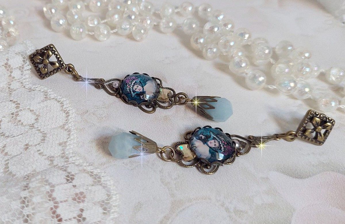 BO Dame au chapeau fleuri repr&eacute;sentant une femme au chapeau entour&eacute; d&rsquo;un ruban noir est mont&eacute; sur des estampes avec des n&oelig;uds en cristal. Une belle &eacute;l&eacute;gance avec ces gouttes en Jade teint&eacute;es de Bleu