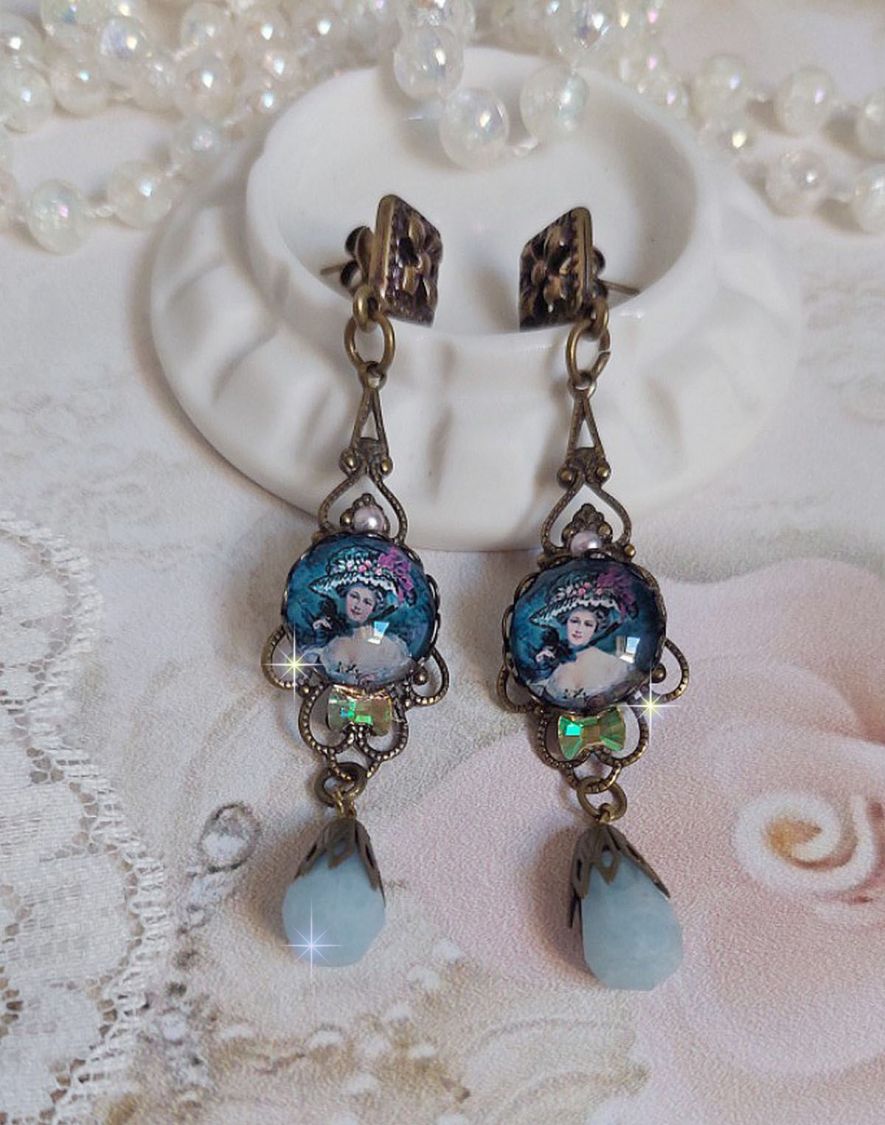BO Dame au chapeau fleuri repr&eacute;sentant une femme au chapeau entour&eacute; d&rsquo;un ruban noir est mont&eacute; sur des estampes avec des n&oelig;uds en cristal. Une belle &eacute;l&eacute;gance avec ces gouttes en Jade teint&eacute;es de Bleu
