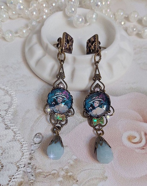 BO Dame au chapeau fleuri repr&eacute;sentant une femme au chapeau entour&eacute; d&rsquo;un ruban noir est mont&eacute; sur des estampes avec des n&oelig;uds en cristal. Une belle &eacute;l&eacute;gance avec ces gouttes en Jade teint&eacute;es de Bleu