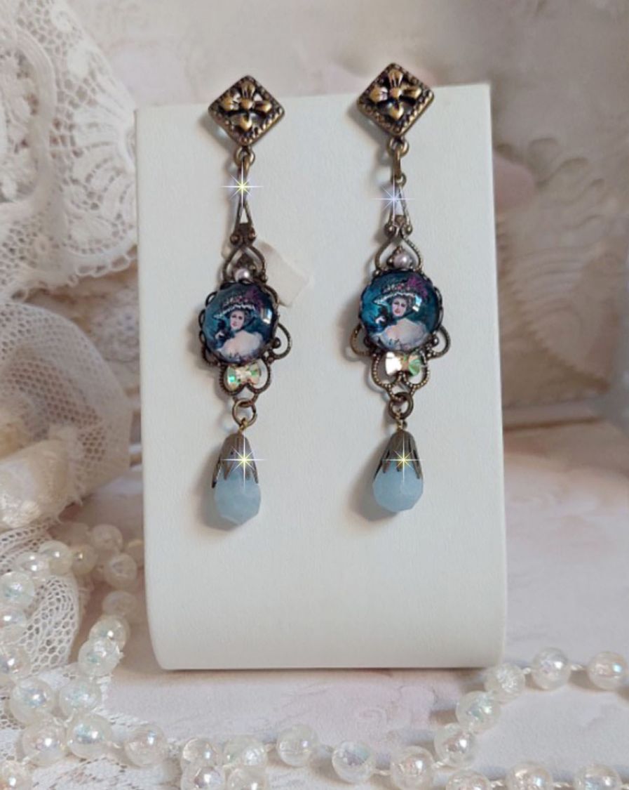 BO Dame au chapeau fleuri repr&eacute;sentant une femme au chapeau entour&eacute; d&rsquo;un ruban noir est mont&eacute; sur des estampes avec des n&oelig;uds en cristal. Une belle &eacute;l&eacute;gance avec ces gouttes en Jade teint&eacute;es de Bleu