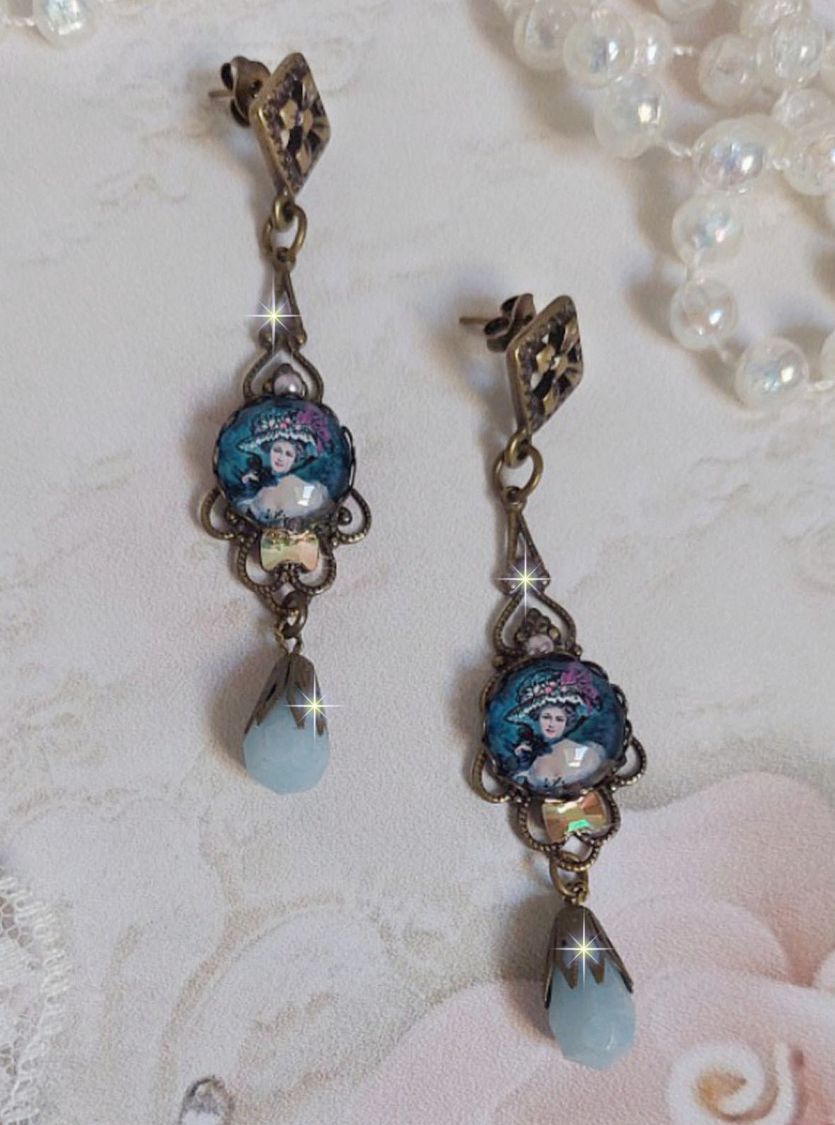 BO Dame au chapeau fleuri repr&eacute;sentant une femme au chapeau entour&eacute; d&rsquo;un ruban noir est mont&eacute; sur des estampes avec des n&oelig;uds en cristal. Une belle &eacute;l&eacute;gance avec ces gouttes en Jade teint&eacute;es de Bleu