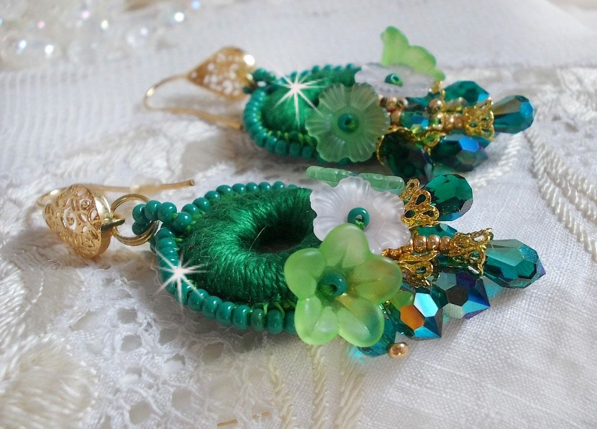 BO Green Iris brod&eacute;es avec du coton DMC Vert sur des anneaux en bois &agrave; laquelle s&rsquo;ajoute des gouttes en cristal, fleurs lucites et rocailles. Mont&eacute;s sur boucles en Laiton. Un style Contemporain !
