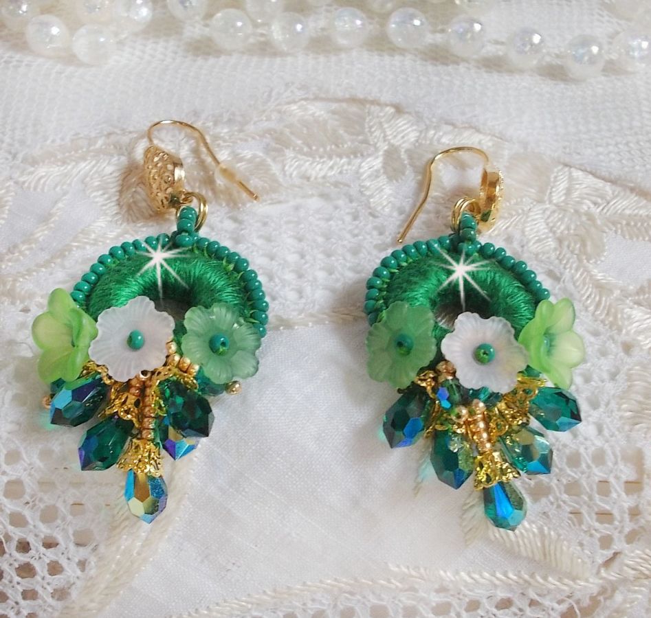 BO Green Iris brod&eacute;es avec du coton DMC Vert sur des anneaux en bois &agrave; laquelle s&rsquo;ajoute des gouttes en cristal, fleurs lucites et rocailles. Mont&eacute;s sur boucles en Laiton. Un style Contemporain !