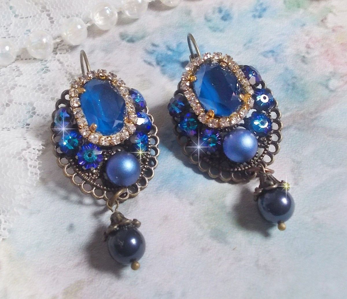 BO Leila avec des cabochons ovales de couleur Royal Blue &agrave; laquelle s&rsquo;ajoute des cabochons ronds, perles nacr&eacute;es et fleurs. Ils sont tous en Cristal, les dormeuses couleur Bronze sont en Laiton