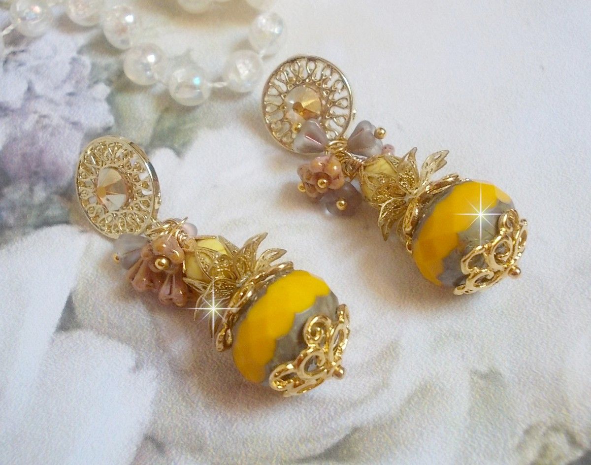 BO Lumi&egrave;re Opale Jaune avec des perles potirons jaunes &agrave; laquelle s&rsquo;ajoute des fleurs, cabochons en cristal, coupelles et perles rondes. Mont&eacute;s sur clous d&rsquo;oreilles en M&eacute;tal. Un style moderne