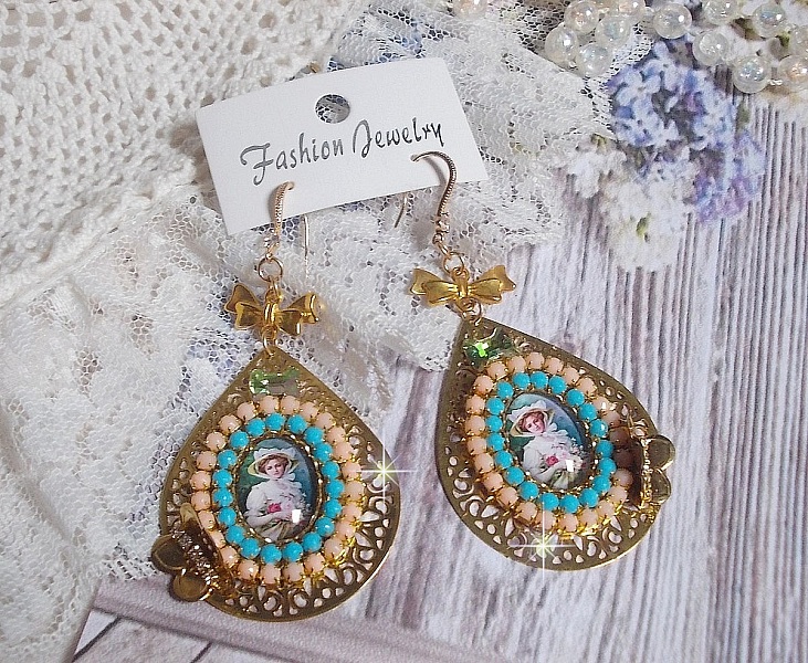 BO Mademoiselle Noellia avec des cabochons ovales repr&eacute;sentant une femme avec un chapeau et un n&oelig;ud blanc &agrave; laquelle s&rsquo;ajoute des cristaux, cha&icirc;nes strass P&ecirc;che et Turquoise sur crochets en plaqu&eacute; Or