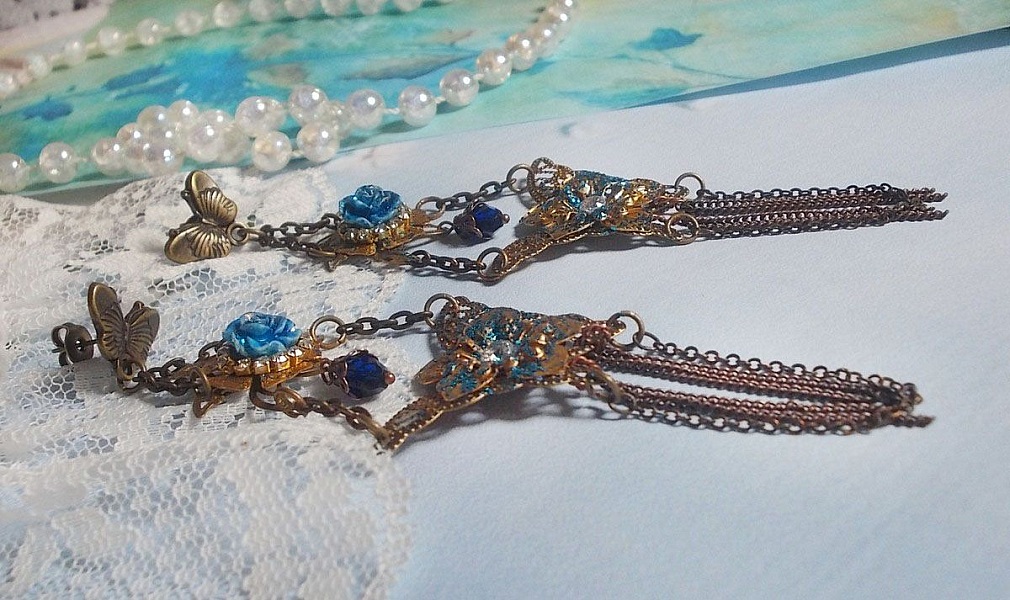 BO Papillons Iris&eacute;s mont&eacute;s sur estampes paillet&eacute;es de Bleu et Bronze, cabochons en forme de rose &agrave; laquelle s&rsquo;ajoute : coupelles fleurs, cha&icirc;ne strass, Zirconiums Cristal et gouttes Cobalt