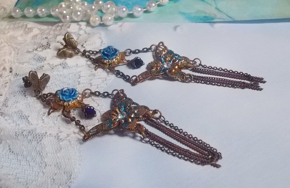 BO Papillons Iris&eacute;s mont&eacute;s sur estampes paillet&eacute;es de Bleu et Bronze, cabochons en forme de rose &agrave; laquelle s&rsquo;ajoute : coupelles fleurs, cha&icirc;ne strass, Zirconiums Cristal et gouttes Cobalt