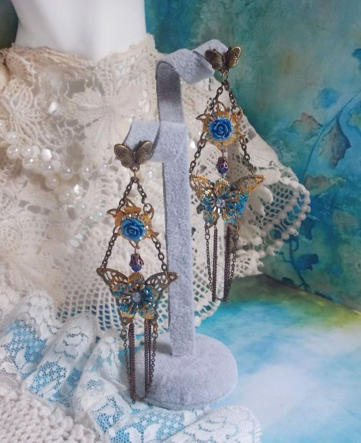 BO Papillons Iris&eacute;s mont&eacute;s sur estampes paillet&eacute;es de Bleu et Bronze, cabochons en forme de rose &agrave; laquelle s&rsquo;ajoute : coupelles fleurs, cha&icirc;ne strass, Zirconiums Cristal et gouttes Cobalt