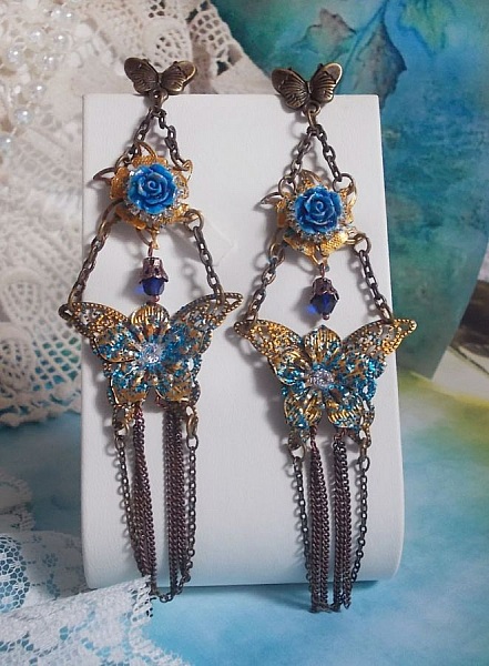 BO Papillons Iris&eacute;s mont&eacute;s sur estampes paillet&eacute;es de Bleu et Bronze, cabochons en forme de rose &agrave; laquelle s&rsquo;ajoute : coupelles fleurs, cha&icirc;ne strass, Zirconiums Cristal et gouttes Cobalt