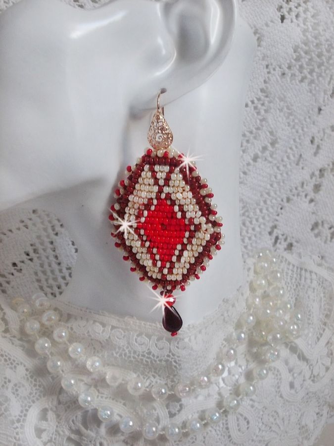 BO Romane brod&eacute;es avec des rocailles en verre Rouge, Bordeaux, Ivoire &agrave; laquelle s'ajoute des gouttes plates Grenat. Le tout est mont&eacute; sur des crochets en Laiton d&eacute;cor goutte