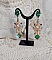 BO Royal Marguerite mont&eacute;es avec des cabochons &agrave; laquelle s&rsquo;ajoute des strass sur les pendentifs Dor&eacute;s. Les pendants sont en r&eacute;sine &eacute;poxy avec clous d&rsquo;oreilles &eacute;maill&eacute;s