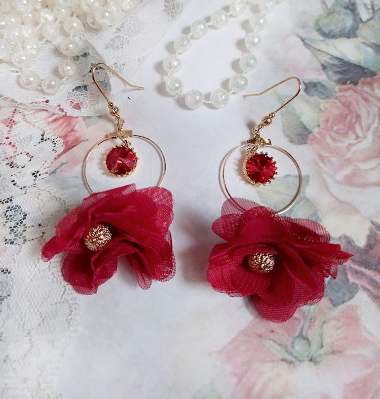 Boucles d'oreilles créoles dorées avec fleurs rouges et cristaux.