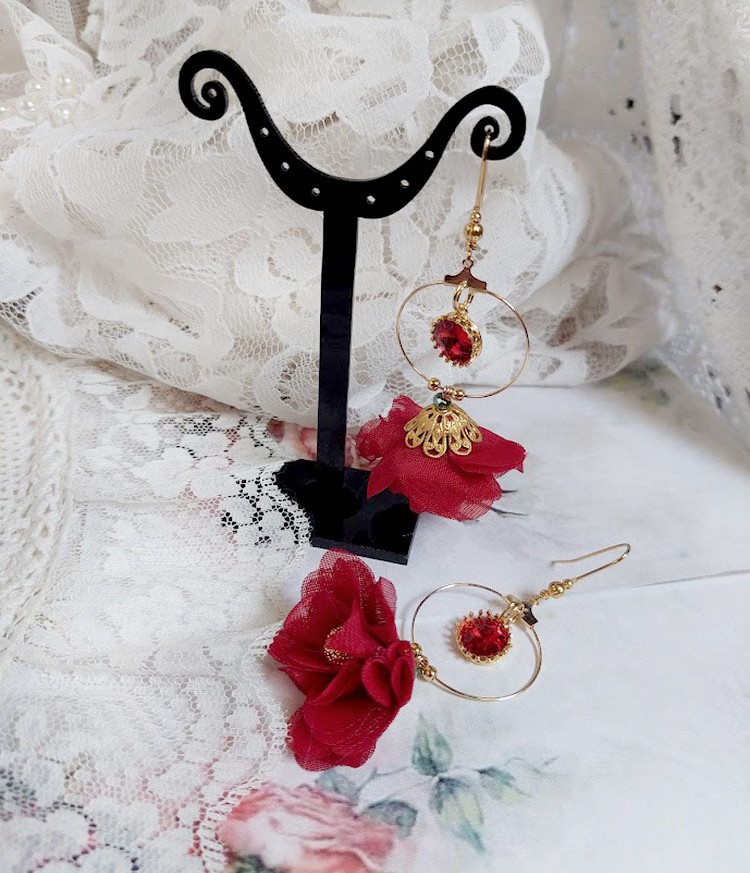 Boucles d'oreilles créoles dorées avec fleurs rouges et cristaux.