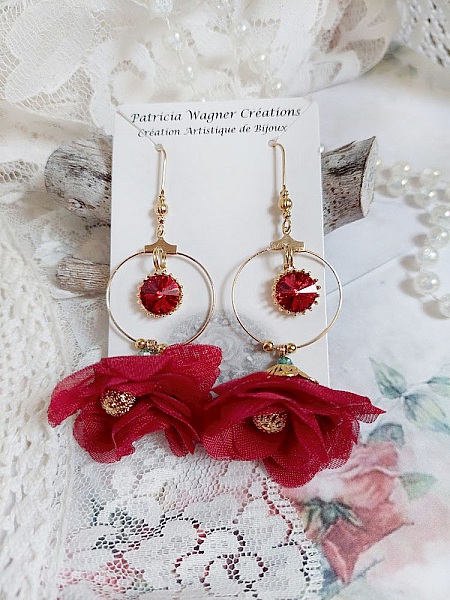 Boucles d'oreilles créoles dorées avec fleurs rouges et cristaux.
