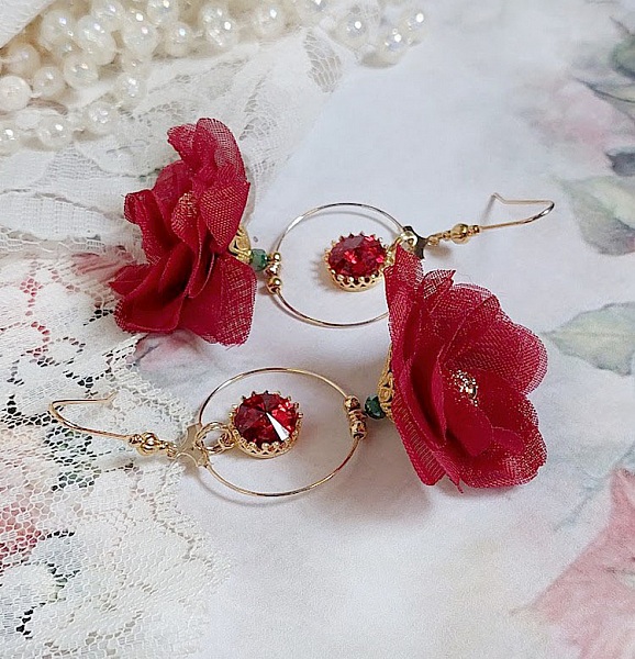 Boucles d'oreilles créoles dorées avec fleurs rouges et cristaux.