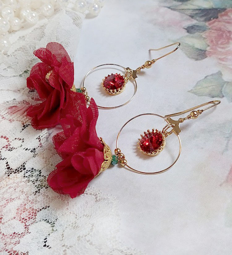 Boucles d'oreilles créoles dorées avec fleurs rouges et cristaux.