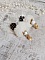 BO Cassandre avec des pierres de gemme : le Howlite Blanc &agrave; laquelle s&rsquo;ajoute des pompons, des intercalaires rondelles, des coupelles feuilles et breloques. Mont&eacute;s sur des puces Noires et Dor&eacute;es 
