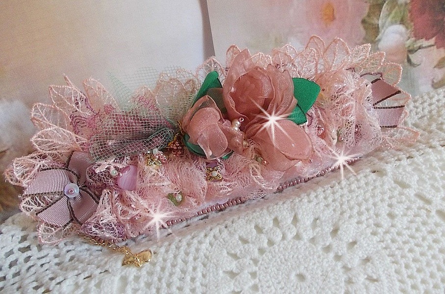 Bracelet Douceur Poudr&eacute;e manchette brod&eacute; avec une dentelle motif floral, ruban organza, tulles, n&oelig;uds, &eacute;tamines, sequins paillettes. La couleur dominante est le Rose &agrave; laquelle s&rsquo;ajoute des cristaux 