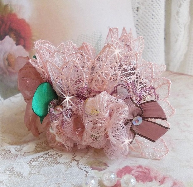 Bracelet Douceur Poudr&eacute;e manchette brod&eacute; avec une dentelle motif floral, ruban organza, tulles, n&oelig;uds, &eacute;tamines, sequins paillettes. La couleur dominante est le Rose &agrave; laquelle s&rsquo;ajoute des cristaux 