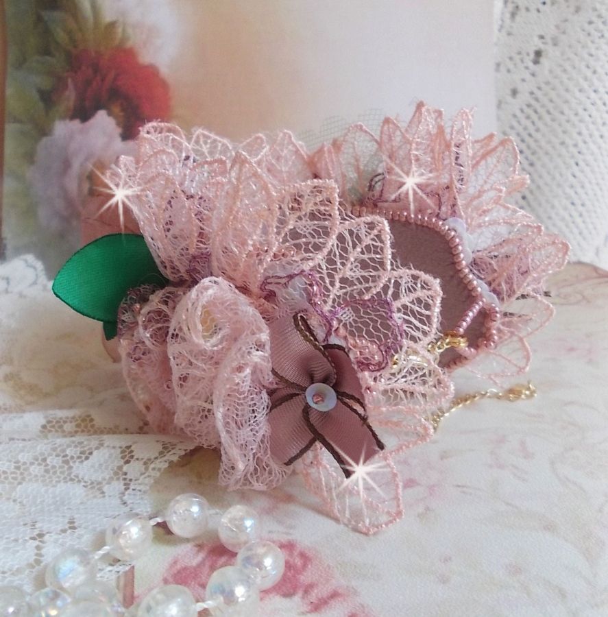 Bracelet Douceur Poudr&eacute;e manchette brod&eacute; avec une dentelle motif floral, ruban organza, tulles, n&oelig;uds, &eacute;tamines, sequins paillettes. La couleur dominante est le Rose &agrave; laquelle s&rsquo;ajoute des cristaux 