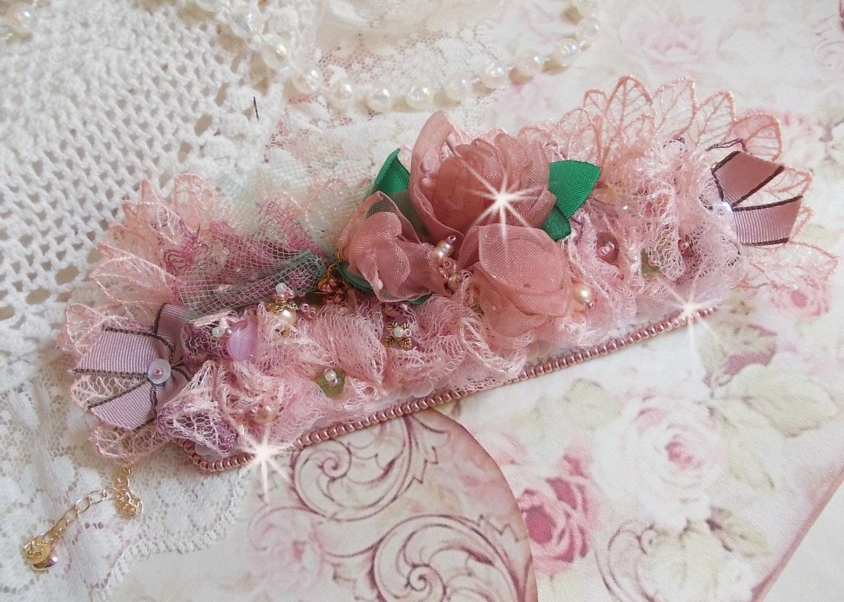 Bracelet Douceur Poudr&eacute;e manchette brod&eacute; avec une dentelle motif floral, ruban organza, tulles, n&oelig;uds, &eacute;tamines, sequins paillettes. La couleur dominante est le Rose &agrave; laquelle s&rsquo;ajoute des cristaux 