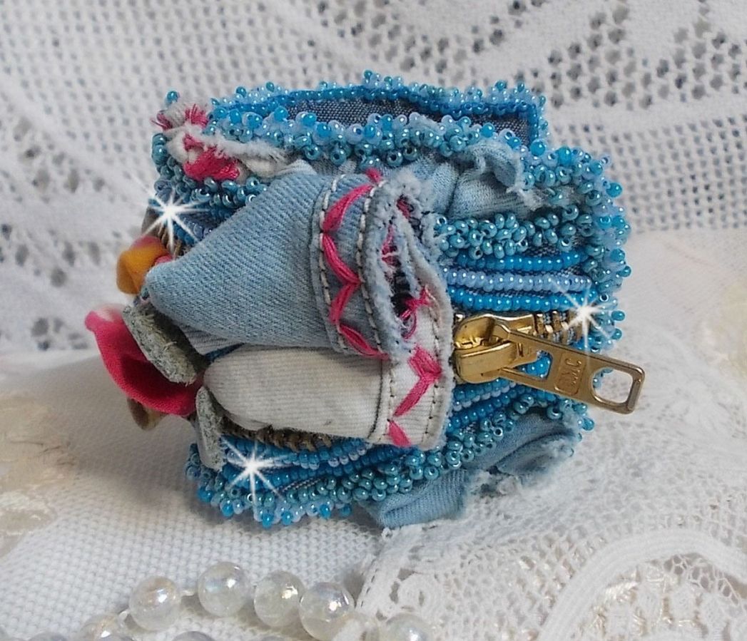 Bracelet manchette en jean brodé avec perles et fermeture éclair.