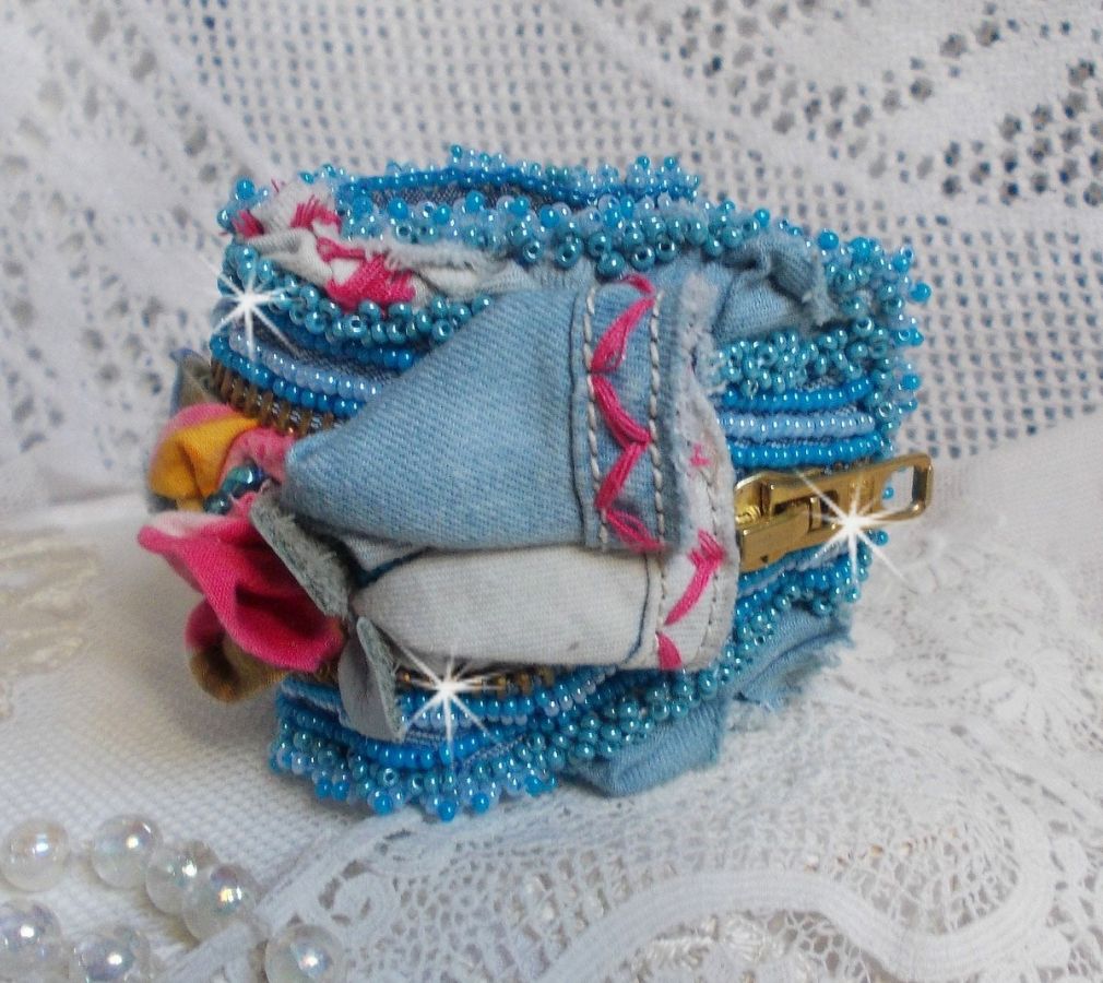 Bracelet manchette en jean brodé avec perles et fermeture éclair.