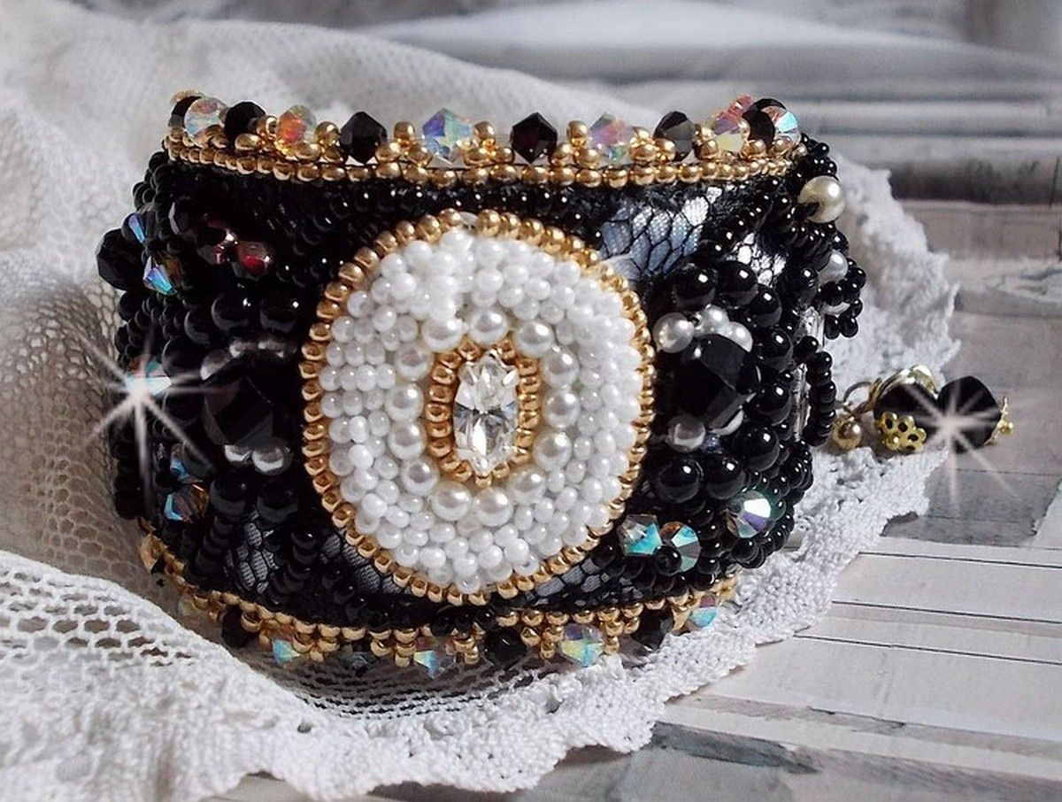 Bracelet Noir Sacr&eacute; Haute Couture brod&eacute; avec des cristaux : navette, h&eacute;lix Bead,, toupies, breloque fleur strass&eacute;e,  perles rondes nacr&eacute;es Verre et rocailles. Les couleurs sont le Noir, Blanc et Dor&eacute;