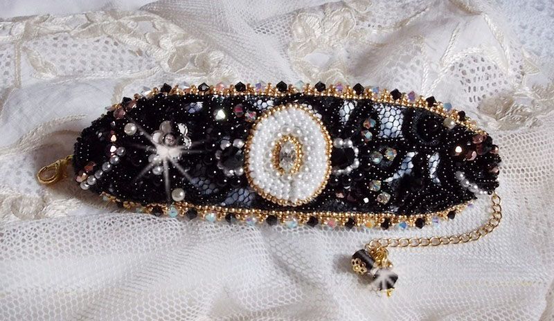 Bracelet Noir Sacr&eacute; Haute Couture brod&eacute; avec des cristaux : navette, h&eacute;lix Bead,, toupies, breloque fleur strass&eacute;e,  perles rondes nacr&eacute;es Verre et rocailles. Les couleurs sont le Noir, Blanc et Dor&eacute;