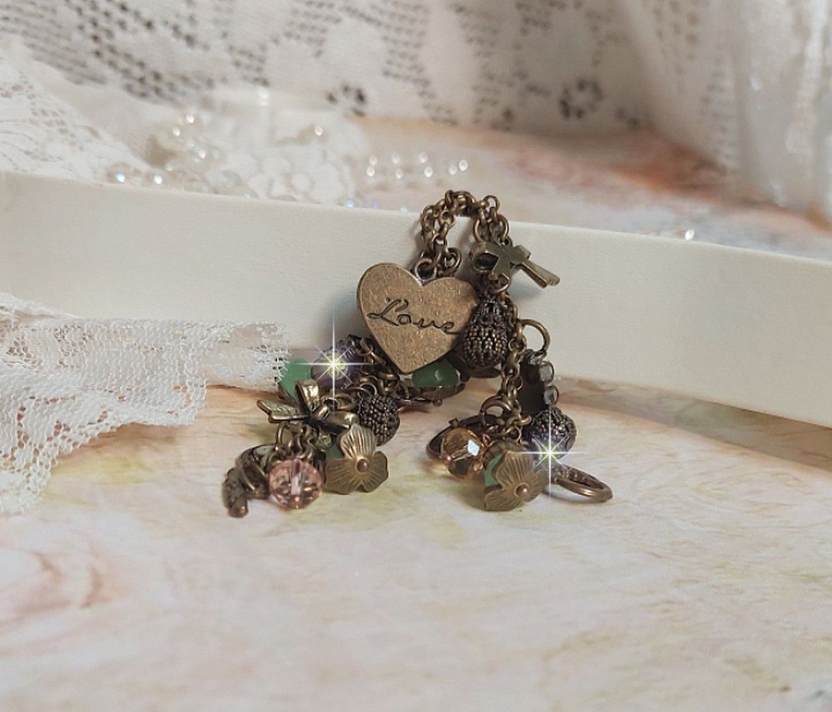 Bracelet Temps d&rsquo;une Folie avec breloques : c&oelig;ur, perles, gouttes filigran&eacute;es, fleurs &eacute;maill&eacute;es, perles rondes, cabochons carr&eacute;s et perles rondes en Verre. Mont&eacute;s sur cha&icirc;nes et fermoir en T Bronze