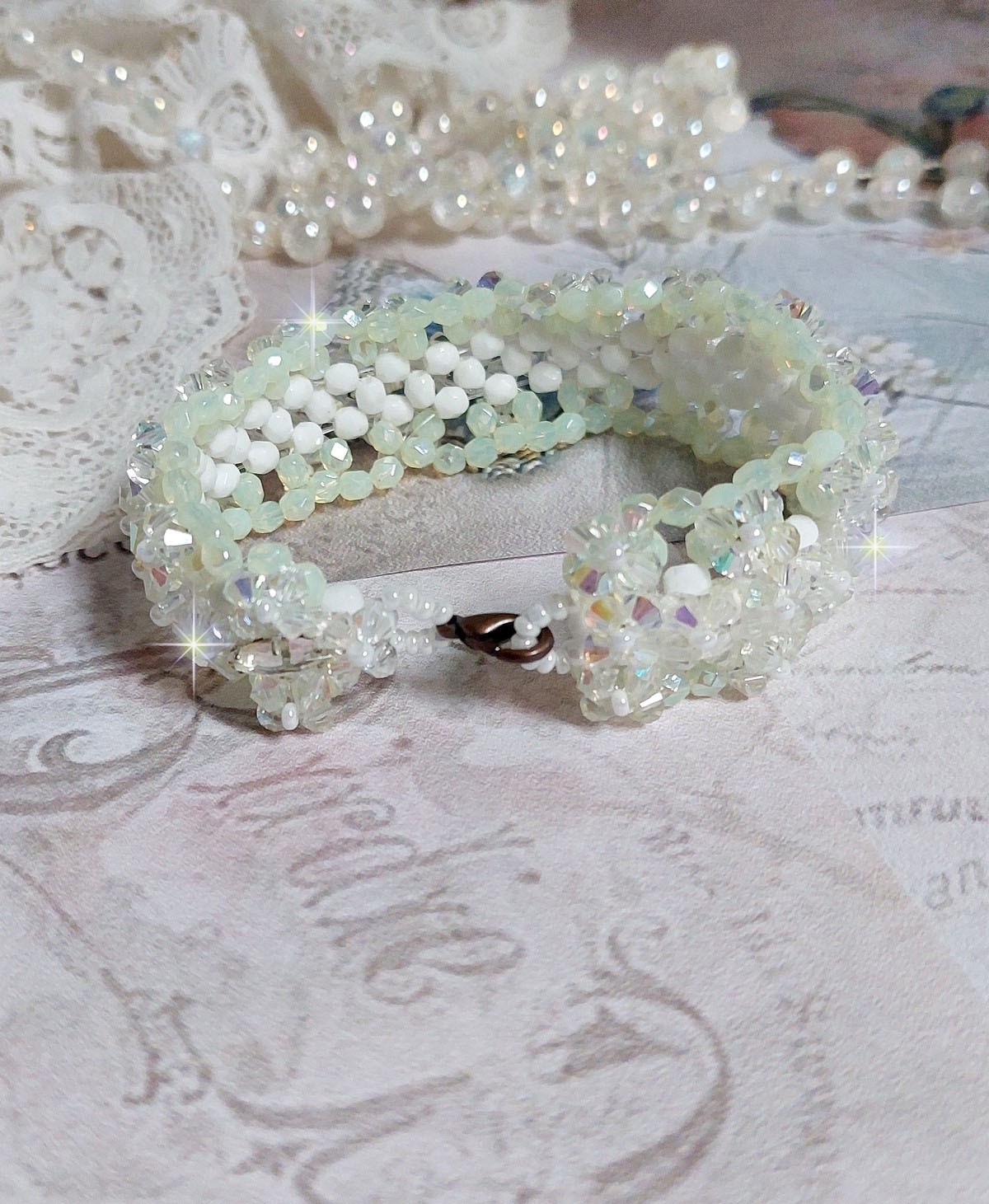 Bracelet V&eacute;nus mont&eacute; avec une cascade de cristaux : toupies et navettes en Cristal AB ainsi que les facettes de couleur Blanche et Beige Opaque de qualit&eacute; AB, puis perl&eacute; de rocailles nacr&eacute;es 