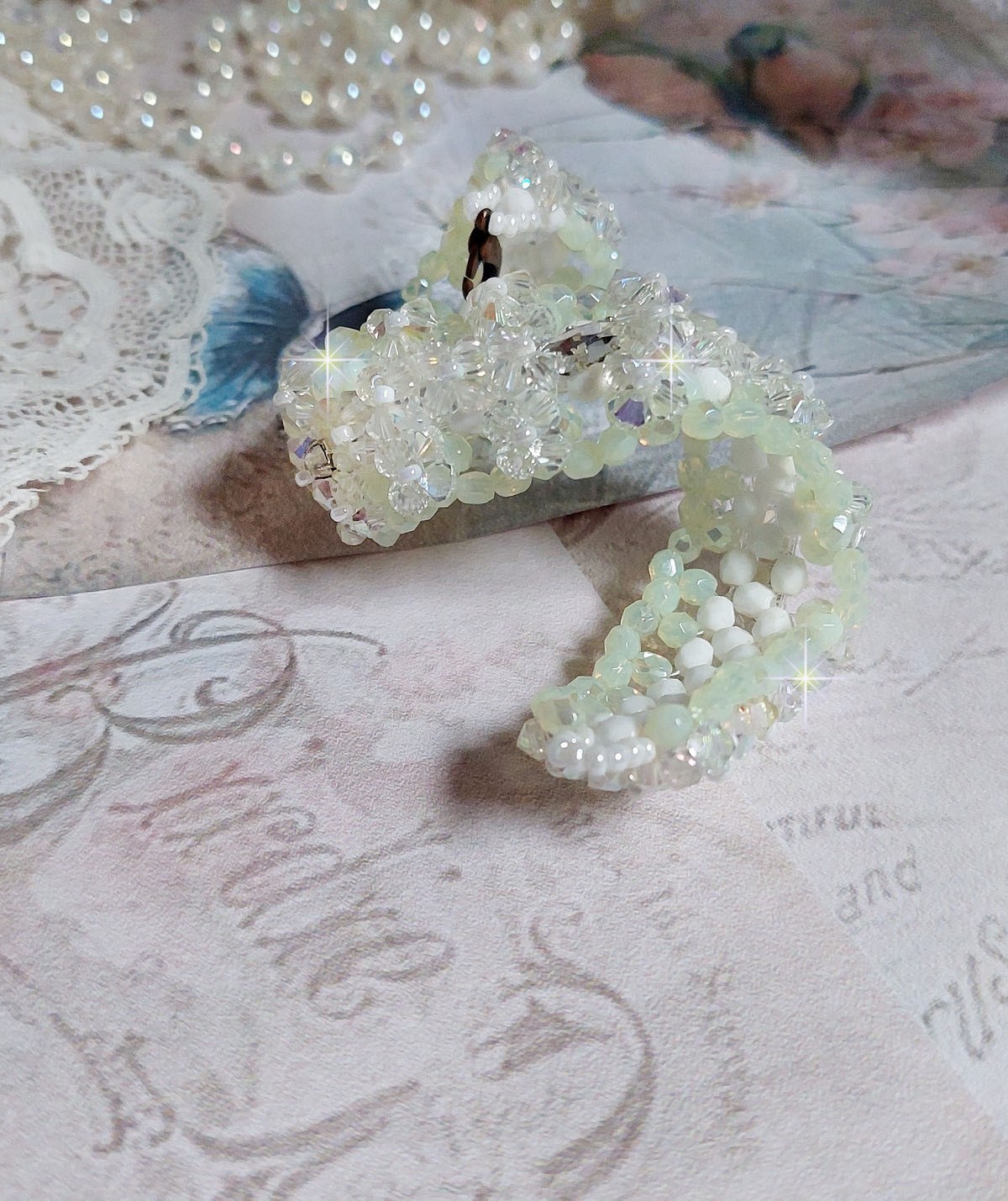 Bracelet V&eacute;nus mont&eacute; avec une cascade de cristaux : toupies et navettes en Cristal AB ainsi que les facettes de couleur Blanche et Beige Opaque de qualit&eacute; AB, puis perl&eacute; de rocailles nacr&eacute;es 