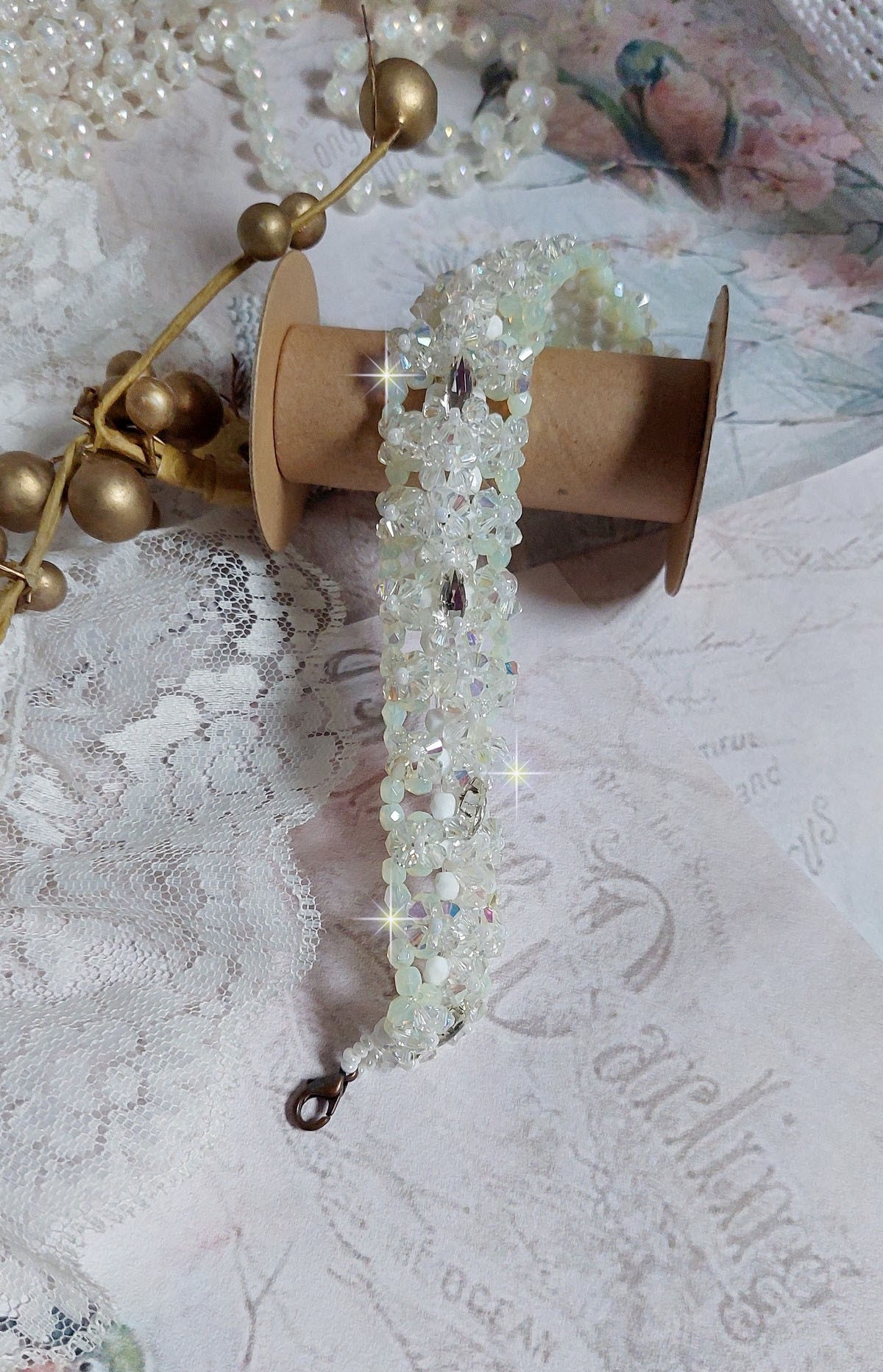 Bracelet V&eacute;nus mont&eacute; avec une cascade de cristaux : toupies et navettes en Cristal AB ainsi que les facettes de couleur Blanche et Beige Opaque de qualit&eacute; AB, puis perl&eacute; de rocailles nacr&eacute;es 