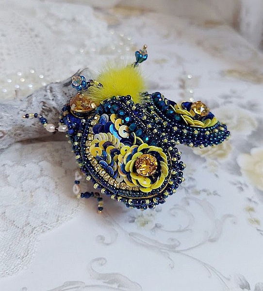 Broche artisanale en forme d'insecte bleu et jaune brodé.