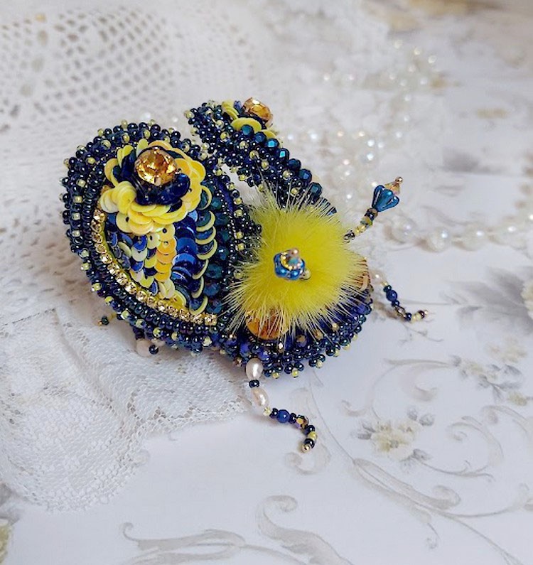 Broche artisanale en forme de scarabée bleu et jaune.