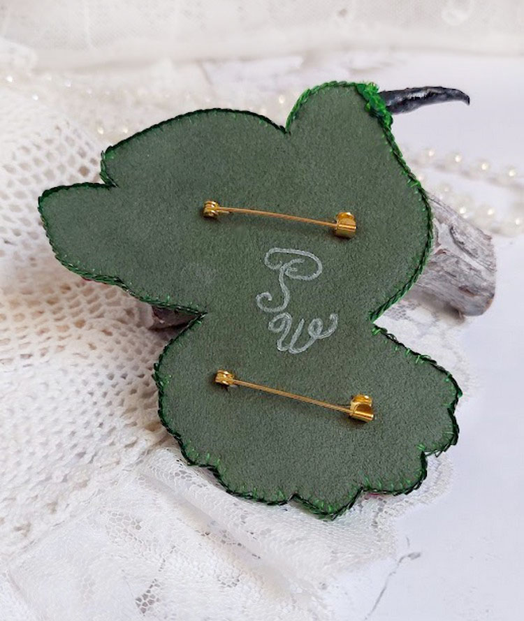 Verso d'une broche colibri brodée avec deux épingles dorées.