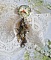 Broche Colombes aux plumages blancs avec des breloques filigran&eacute;es gouttes et lisses, perles rondes et n&oelig;ud en cristal, ruban organza cr&egrave;me, pendentif plaqu&eacute; or avec un zircon sur une broche en m&eacute;tal