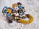 Broche artisanale baroque ornée de fleurs et perles jaunes.