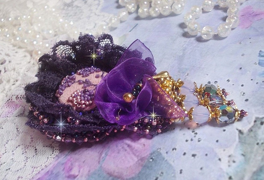Broche Lady Romantique brod&eacute;e avec une dentelle violine ann&eacute;e 1950 avec un tissu en lin vieux rose brod&eacute; de fleurs et branches en rocailles bord&eacute; d&rsquo;un ruban organza, fleurs, cristaux et breloques