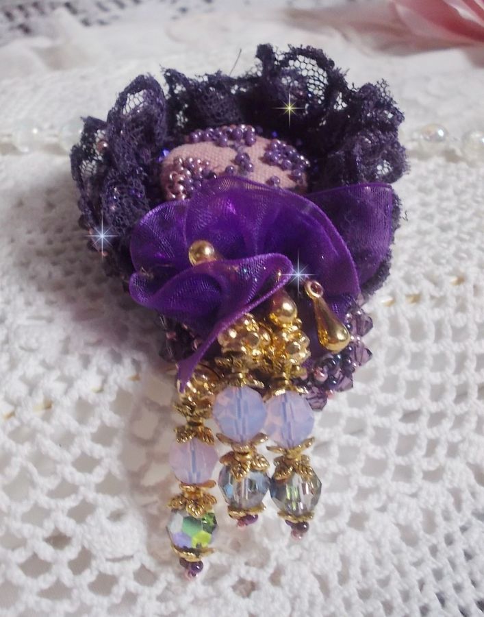 Broche Lady Romantique brod&eacute;e avec une dentelle violine ann&eacute;e 1950 avec un tissu en lin vieux rose brod&eacute; de fleurs et branches en rocailles bord&eacute; d&rsquo;un ruban organza, fleurs, cristaux et breloques