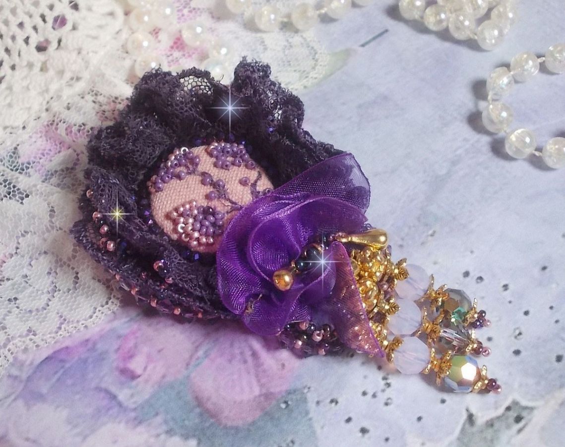 Broche Lady Romantique brod&eacute;e avec une dentelle violine ann&eacute;e 1950 avec un tissu en lin vieux rose brod&eacute; de fleurs et branches en rocailles bord&eacute; d&rsquo;un ruban organza, fleurs, cristaux et breloques
