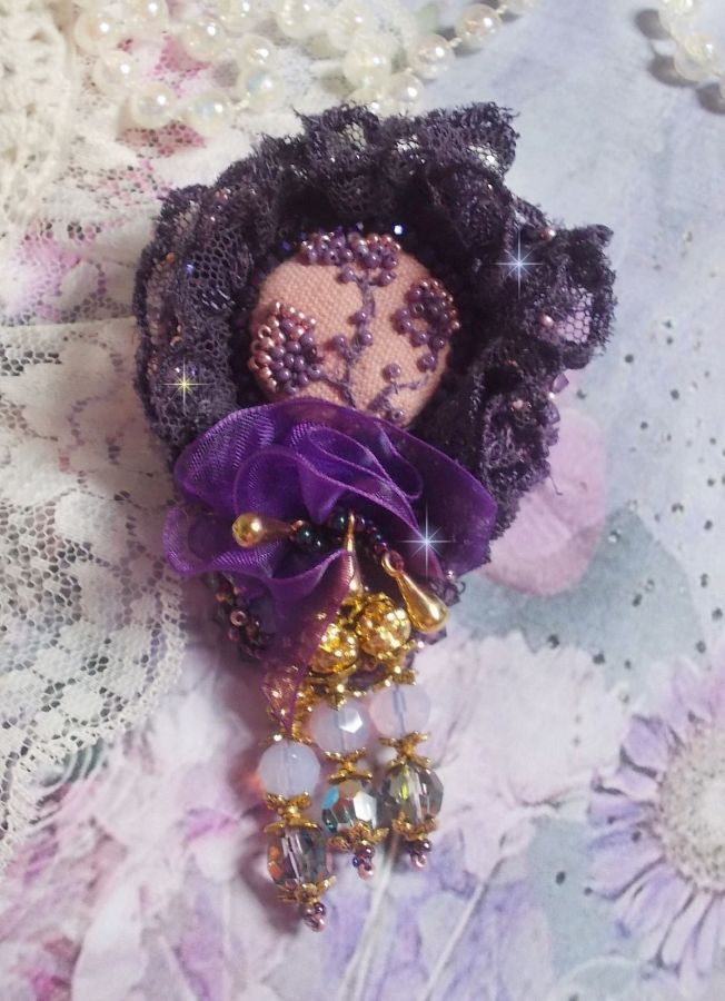 Broche Lady Romantique brod&eacute;e avec une dentelle violine ann&eacute;e 1950 avec un tissu en lin vieux rose brod&eacute; de fleurs et branches en rocailles bord&eacute; d&rsquo;un ruban organza, fleurs, cristaux et breloques